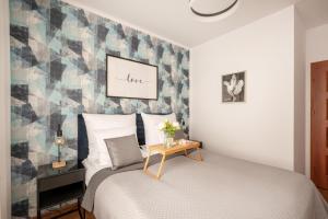 een slaapkamer met een bed met een geometrische accentwand bij Homini Apartament IMPERO z Parkingiem in Poznań
