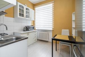 a kitchen with white cabinets and a table and a sink at Pae 52 Apartment, Free Parking ,Airport 2km in Tallinn