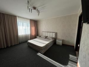 a bedroom with a bed and a large window at Бухар Жырау 76 in Karagandy