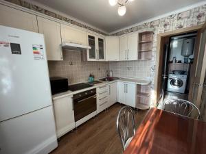 a kitchen with white cabinets and a table and a refrigerator at Бухар Жырау 76 in Karagandy