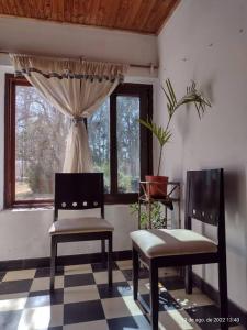 2 chaises assises dans une pièce avec fenêtre dans l'établissement Cabaña Ascensión-Caminos del Vino, à Colonia Las Rosas