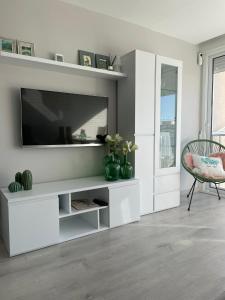 a white living room with a television and a chair at Apartamento Paradis Playa in La Pineda