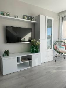 uma sala de estar branca com uma televisão e uma cadeira em Apartamento Paradis Playa em La Pineda