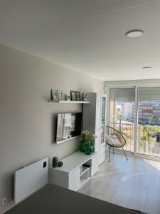uma sala de estar branca com uma televisão e uma cadeira em Apartamento Paradis Playa em La Pineda