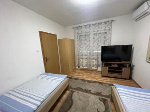 Habitación pequeña con cama y TV de pantalla plana. en Apartmani BROD, en Zenica