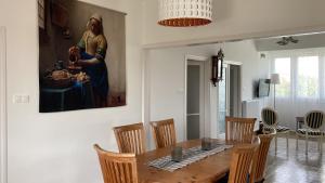 ein Esszimmer mit einem Tisch und einem Gemälde an der Wand in der Unterkunft NAGYGÓLYA Appartementen in Szentistván