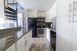 a kitchen with white cabinets and a black refrigerator at Turtle Bay Hale Lani Condo in Kahuku
