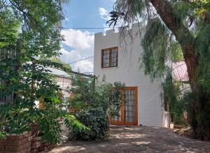 a white house with a tree in front of it at Bethesda Tower Accommodation in Nieu-Bethesda