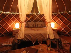 a bedroom with a bed with two glasses on a table at The Warren Yurt in Withyham