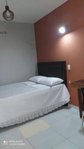 een slaapkamer met een groot bed met witte lakens bij Pousada Mariza in Guarabira