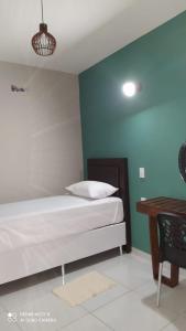 a bedroom with a bed and a wooden table at Pousada Mariza in Guarabira