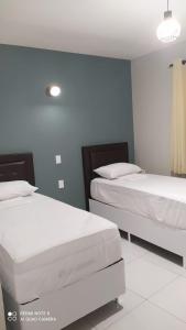 twee bedden in een kamer met blauwe muren bij Pousada Mariza in Guarabira