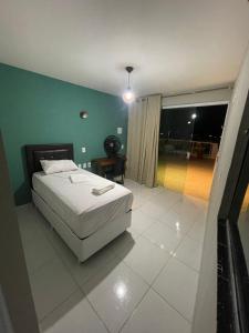 a bedroom with a white bed and a green wall at Pousada Mariza in Guarabira