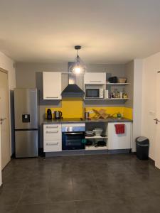  La cuisine est équipée de placards blancs et d'un réfrigérateur. dans l'établissement LEU FLAMBOYANT Appartement 2 pièces, à Saint-Leu