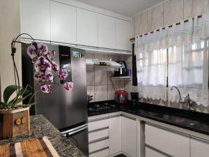 een keuken met witte kasten en een roestvrijstalen koelkast bij Casa em Condomínio Martin de Sa in Caraguatatuba