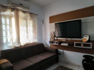 een woonkamer met een bank en een flatscreen-tv bij Casa em Condomínio Martin de Sa in Caraguatatuba