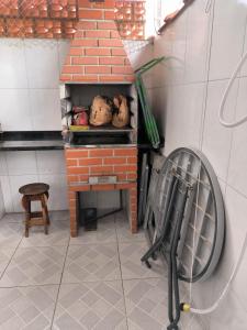 een stenen oven met een stoel in een keuken bij Casa em Condomínio Martin de Sa in Caraguatatuba +2 foto's