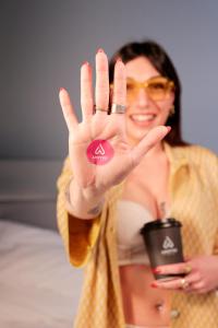 a woman holding up her hand with a pink sticker on it at Arryvo Hotel in Lecce