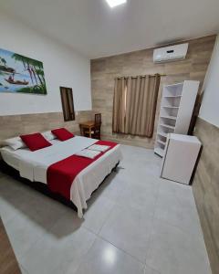 um quarto com uma cama com um cobertor vermelho e branco em Pousada Águas Douradas em Aracaju