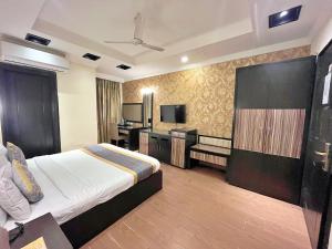 ein Hotelzimmer mit einem Bett und einem Flachbild-TV in der Unterkunft The Oakland Plaza by Orion Hotels in Neu-Delhi