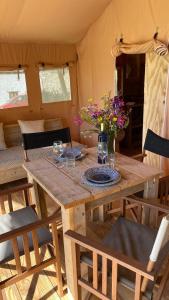 een houten tafel met glazen en bloemen erop bij Tienda de Safari Almagro in Montecorto