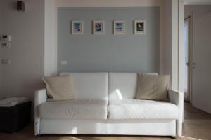 a white couch in a living room with pictures on the wall at Bertoldi Terme sul Garda - Terrazza in Nago-Torbole