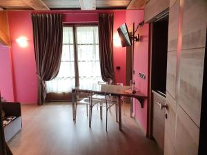 une salle à manger aux murs roses avec une table et des chaises dans l'établissement Residence Hotel Serenella, à Aprica