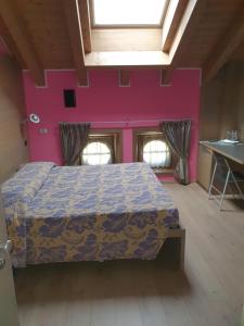 1 dormitorio con cama y pared de color rosa en Residence Hotel Serenella, en Aprica