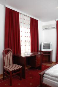 Cette chambre comprend un bureau, un lit et une télévision. dans l'établissement Vila Lux Milikic, à Kraljevo