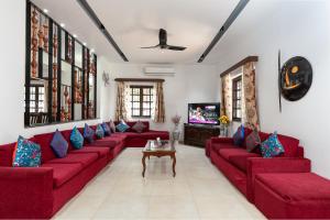 a living room with red couches and a tv at Lavish Executive Villa with Private Swimming Pool in Calangute