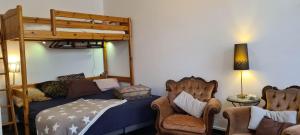 sypialnia z łóżkiem piętrowym i 2 krzesłami w obiekcie Chaleureux studio indépendant w mieście Encausse-les-Thermes
