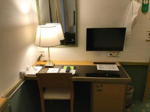 a room with a desk with a lamp and a television at Hotel Arlette Beim Hauptbahnhof in Zurich