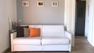 a white couch with an orange pillow on it in a room at Bertoldi Terme sul Garda - Matthew in Nago-Torbole