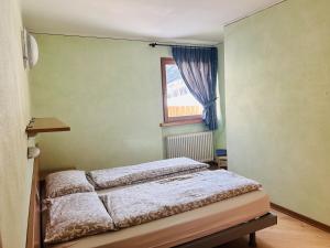mała sypialnia z łóżkiem i oknem w obiekcie Appartamento Breva w Livigno