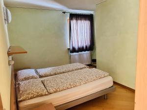 łóżko w pokoju z oknem w obiekcie Appartamento Breva w Livigno