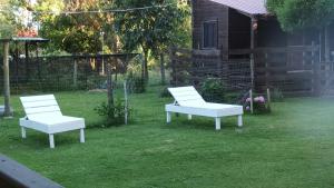 two white chairs and a bench in a yard at • Cabaña Las Hortensias • in La Pedrera +3 photos