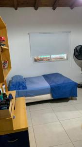 1 dormitorio con 1 cama con edredón azul y ventana en Disfrute y relax en Luján de Cuyo
