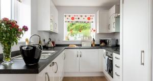a kitchen with white cabinets and a sink and a window at Plover 3 - The Cove in Brixham