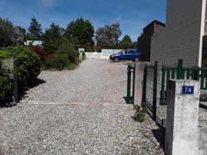 una entrada con una valla y un coche azul aparcado en Studio à la mer, en Criel-sur-Mer