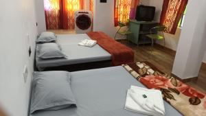 a room with two beds and a tv in it at Jag Niwas Guest House & pure veg restaurant in Udaipur