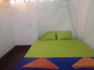 a small room with a green bed and two pillows at Happiness Guesthouse in Koh Rong Sanloem