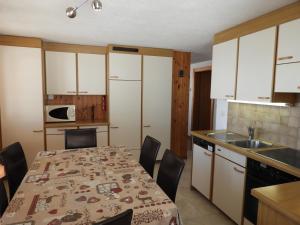 uma cozinha com mesa e cadeiras e uma cozinha com armários brancos em Malva em Belalp
