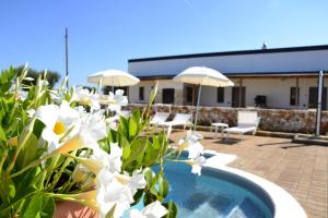 una piscina con fiori bianchi e ombrelloni di Agriturismo Masseria Alberotanza a Conversano