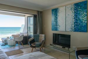 a living room with a tv and a room with the ocean at De Branders Woonstel No 56 & 67 in Hartenbos