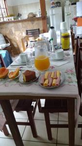 einem Tisch mit Teller mit Lebensmitteln und einem Krug Orangensaft in der Unterkunft Suites Pouso Familiar José e Maria in Paraty