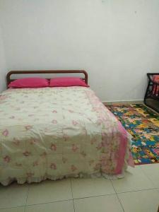 a bedroom with a bed with a pink comforter at Homestay Pelangi Mall Kota Bharu in Kota Bharu