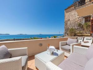 un patio con sillas blancas, una mesa y el océano en Villa Ana Apartments, en Mlini