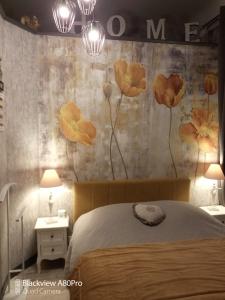 1 dormitorio con 1 cama con flores en la pared en Studio Malou, cuisine, salle d'eau, terrasse amenagée, en Olliergues