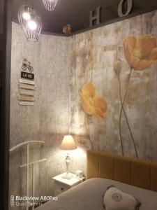 1 dormitorio con 1 cama y flores en la pared en Studio Malou, cuisine, salle d'eau, terrasse amenagée, en Olliergues
