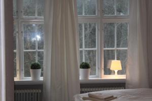 a bedroom with a window with potted plants and a lamp at Vallarnas Bed & Breakfast in Falkenberg